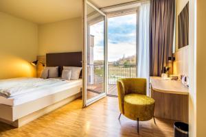 a hotel room with a bed and a balcony at Lagovida Das Ferienresort Am Störmthaler See in Großpösna