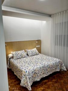 a bedroom with a bed with a comforter and pillows at Hostal Charo II in Santiago de Compostela