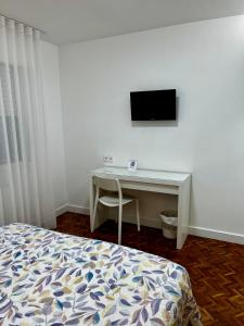 a bedroom with a bed and a desk with a television at Hostal Charo II in Santiago de Compostela