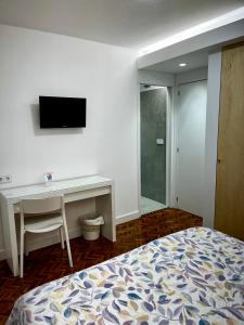 Dormitorio con cama, escritorio y TV en Hostal Charo II, en Santiago de Compostela