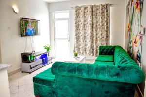 a living room with a green couch in front of a window at Mogul's Palace (3 beds) Thika town in Thika