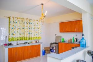 a kitchen with wooden cabinets and a yellow curtain at Mogul's Palace (3 beds) Thika town in Thika