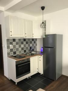 a kitchen with white cabinets and a black refrigerator at Hestia Apartments in Berovo