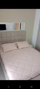 a large white bed with pink pillows and a window at Appartement costa mar Martil in Martil