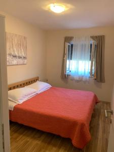 1 dormitorio con 1 cama con manta roja y ventana en Villa Angela Lucia, en Stomorska