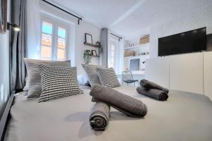 um quarto com uma cama com almofadas e uma televisão em Studio de Luxe au Cœur de Grasse em Grasse