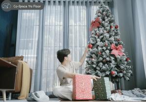 un hombre está decorando un árbol de Navidad con regalos en Scene Private hostel, en Nan