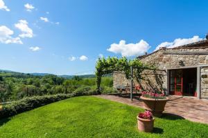 a stone house with a yard with a green lawn at Primerose in Greve in Chianti