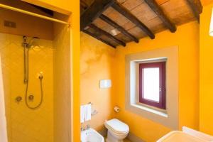 a yellow bathroom with a shower and a toilet at Primerose in Greve in Chianti