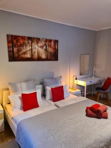 - une chambre avec un grand lit blanc et des oreillers rouges dans l'établissement Waldblick Ferienwohnungen, à Bonndorf im Schwarzwald