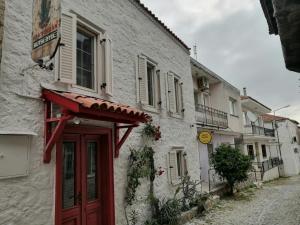 a white building with a red door on a street at kaktüshan otel in Alaçatı