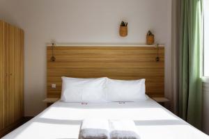 フレジュスにあるL'Oasis Hotelの白いベッド1台(木製ヘッドボード付)が備わるベッドルーム1室が備わります。