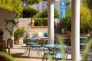 un patio con tavoli, sedie e recinzione di L'Oasis Hotel a Fréjus