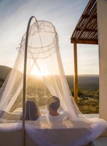 a couple laying in a canopy bed with the sunset at Simbavati Cederberg Ridge in Clanwilliam