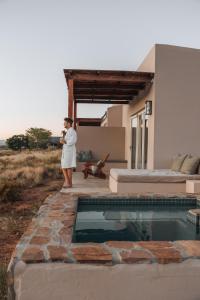 a woman standing next to a house with a swimming pool at Simbavati Cederberg Ridge in Clanwilliam