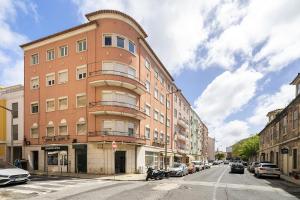 a tall brick building on a city street with parked cars at Cozy Apt in Lisbon with Terrace by Soulplaces in Lisbon