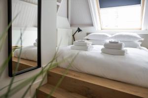 a bedroom with a bed with white pillows and a mirror at The Guest Apartments - Lange Putstraat in Den Bosch
