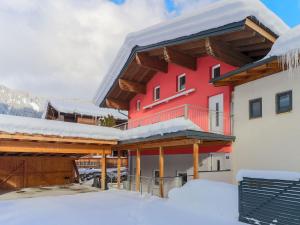 un gran edificio rojo con nieve en el suelo en Luxurious Holiday Home in Krimml with Sauna, en Krimml