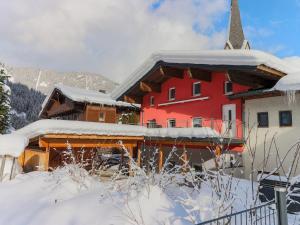 un gran edificio rojo con techo cubierto de nieve en Luxurious Holiday Home in Krimml with Sauna, en Krimml