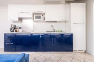 a white kitchen with blue cabinets and a sink at Residence Villa degli Aranci in Riva del Garda
