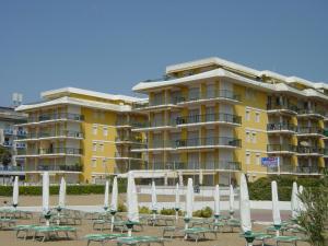 ein gelbes Gebäude mit Tischen und Stühlen davor in der Unterkunft Residence Il Panfilo sul Mare in Lido di Jesolo