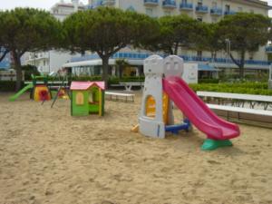 einen Spielplatz mit Rutsche im Sand in der Unterkunft Residence Il Panfilo sul Mare in Lido di Jesolo