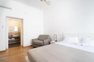 a bedroom with a white bed and a chair at L'isola che c'è - Appartamento in Cagliari