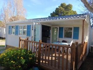 a small white cottage with a wooden deck at Mobile-home climatisé 5 couchages in Narbonne-Plage