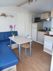 a small kitchen with a table and a blue couch at Mobile-home climatisé 5 couchages in Narbonne-Plage