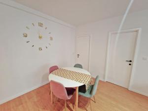 a dining room with a table and chairs and a clock at Le cocon du midi - Appartement Cosy in Brussels