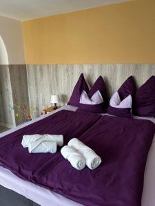 ein violettes Bett mit zwei Paar Handtüchern darauf in der Unterkunft Apartment Révész in Harkány