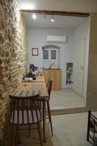 a kitchen with a table and chairs and a stone wall at DePaolis Corfu Town Apartment in Corfu Town