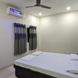 a room with a bed with curtains and a fan at AATITHYA HOME STAY in Ujjain