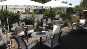 eine Gruppe von Tischen und Stühlen mit weißen Sonnenschirmen in der Unterkunft Ferienweingut & Gutsrestaurant Becker in Burgen
