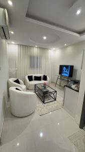 a living room with two white couches and a tv at Narcissus suite in Riyadh