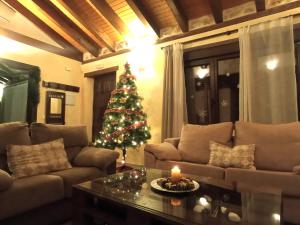 een kerstboom in een woonkamer met een bank bij Casa Entre Hoces810paxJardín y barbacoa in Fuentemizarra