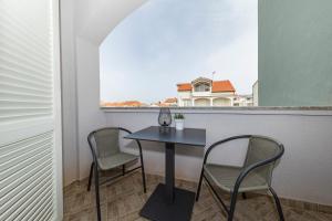 a table and chairs in a balcony with a window at Apartment Nea Zadar in Zadar