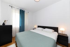 a white bedroom with a large bed with two lamps at Apartment Nea Zadar in Zadar