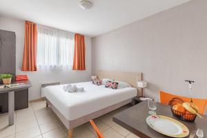 ein Hotelzimmer mit einem weißen Bett und einem Tisch in der Unterkunft Appart'City Classic Marseille Aéroport - Vitrolles in Vitrolles