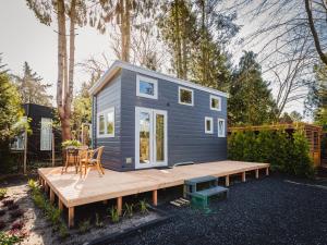 una casa pequeña sentada en una terraza de madera en vakantiehuisje Tiny house met sauna in de bossen van de Veluwe, en Putten