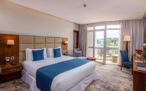 カンパラにあるGolden Tulip Canaan Kampalaの大きなベッドと窓が備わるホテルルームです。