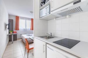 eine Küche mit einem Waschbecken und ein Zimmer mit einem Bett in der Unterkunft Appart'City Classic Marseille Aéroport - Vitrolles in Vitrolles