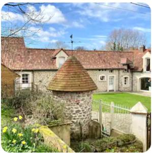 ein altes Steinhaus mit einem Zaun und einem Hof in der Unterkunft La Grange Dimière in Saint-Martin-Boulogne