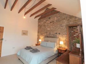 a bedroom with a bed and a brick wall at Cartshed in Kelso