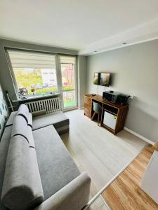a living room with a couch and a desk with a television at Pokoje Gościnne in Kołobrzeg