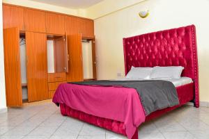 a large bed with a red headboard in a room at DESIRED 2 BEDROOM Apartment in Thika