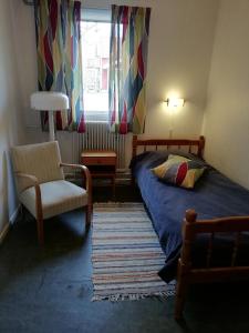 um quarto com uma cama, uma cadeira e uma janela em Moshults Vandrarhem em Moshultamåla
