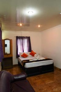 Misty Hills Munnar في مونار: غرفة نوم بسرير ومرآة وأريكة