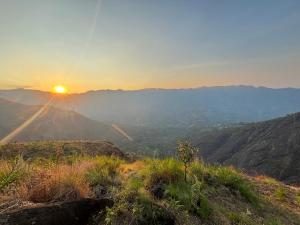 a view of the sun setting over a mountain range at Hide away valley in Kodaikānāl