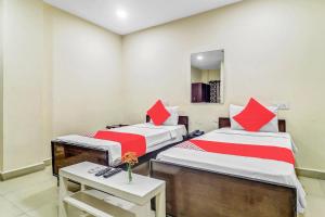 two beds in a room with a table and a mirror at Hotel Airport Shine Inn in Shamshabad